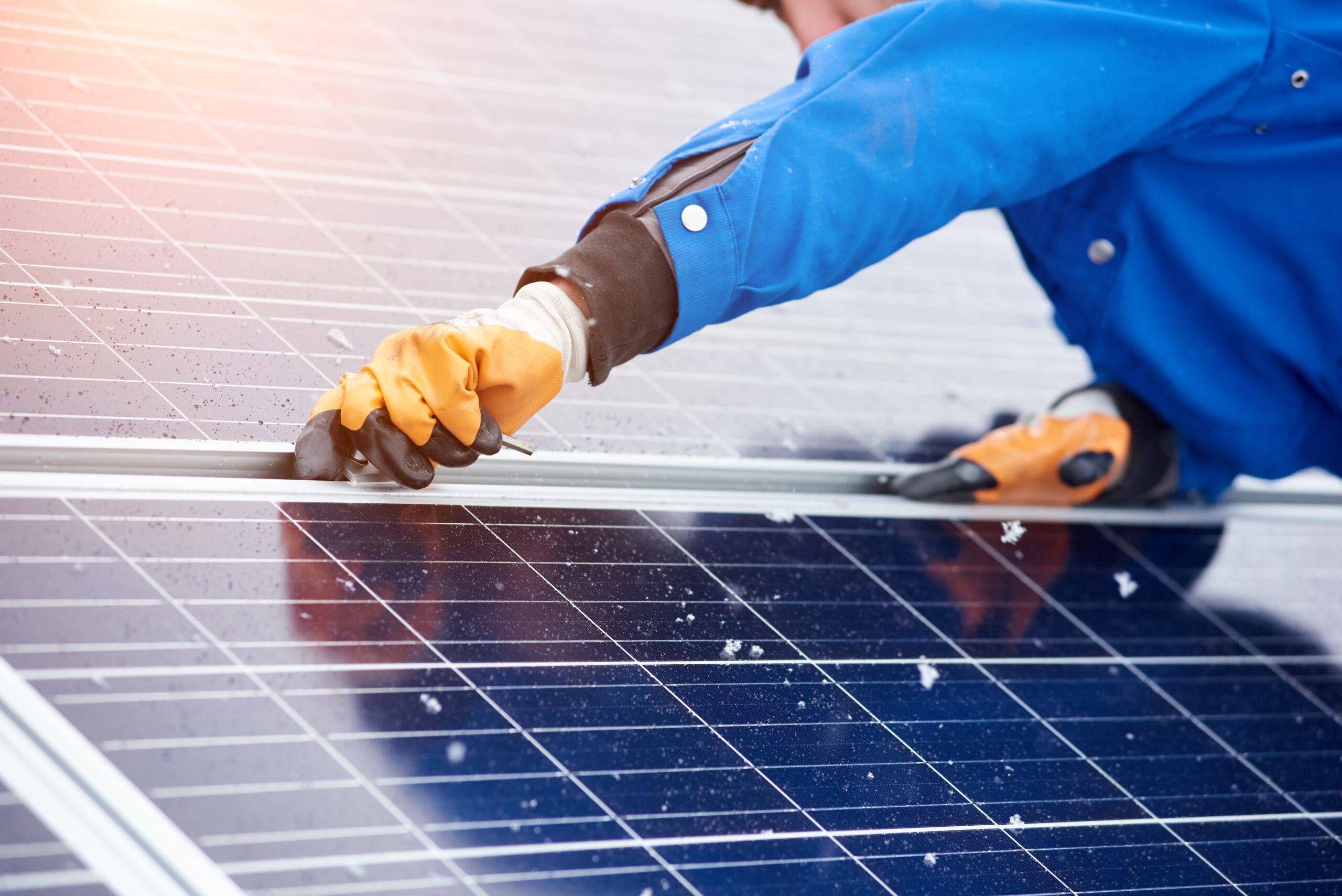 Horizontale Nahaufnahme eines Arbeiters, der Solarzellen auf einem Kraftwerk installiert, das alternative erneuerbare Energien nutzt.
