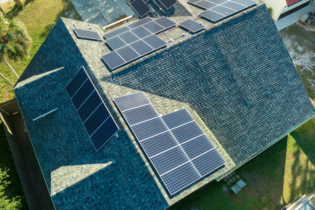 Luftaufnahme des Daches eines Gebäudes mit blauen Photovoltaikmodulen zur Erzeugung sauberer, ökologischer elektrischer Energie.
