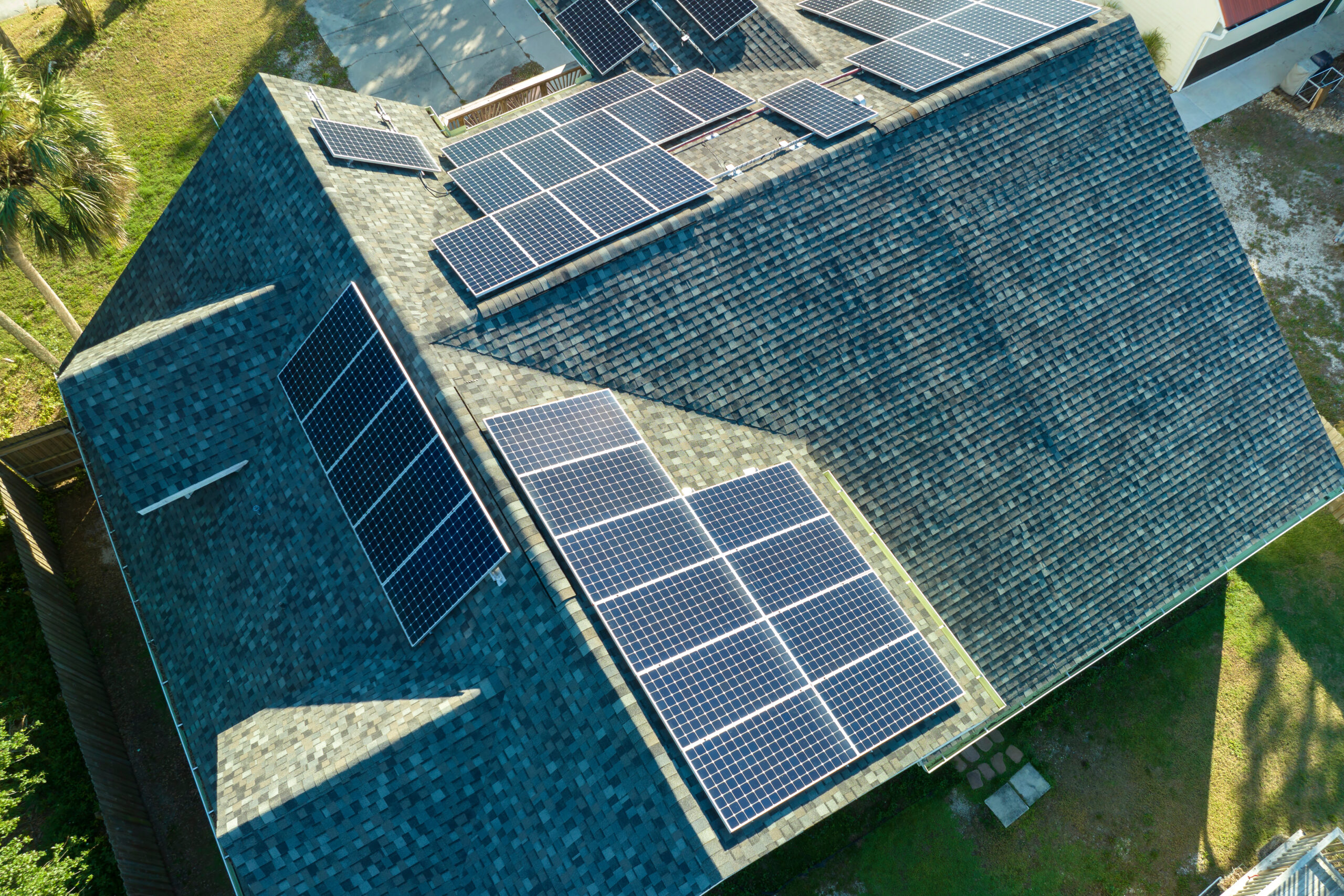 Luftaufnahme des Daches eines Gebäudes mit blauen Photovoltaikmodulen zur Erzeugung sauberer, ökologischer elektrischer Energie.
