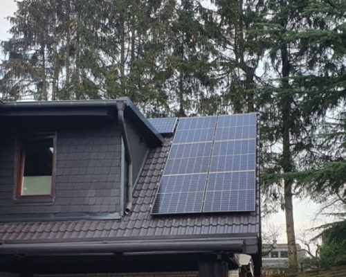 Dunkles Dach mit Gaube und Fenster. Umbaut mit Solarmodulen.