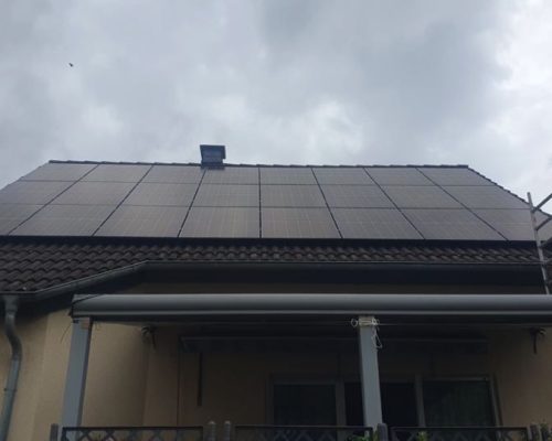 Ansicht von vorne, von einer Solaranlage auf einem Dach. Montage-Gerüst vor dem beigen Haus.