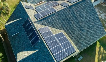 Aerial view of american building roof with blue solar photovoltaic panels for producing clean ecological electric energy. Investing in renewable electricity for retirement income concept.
