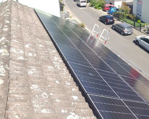 Ansicht eines Dachteils und der Straße vor dem Haus. Solarkollektoren am vorderen Dachteil.
