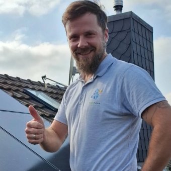 Aufnahme von Armin Welter auf dem Dach stehend. Der rechte Daumen wird nach oben gestreckt. Im Hintergrund eine Solaranlage.