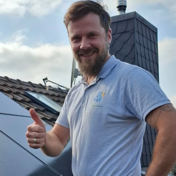 Aufnahme von Armin Welter auf dem Dach stehend. Der rechte Daumen wird nach oben gestreckt. Im Hintergrund eine Solaranlage.